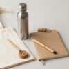 Articulos promocionales ecologicos sobre lino claro: bolsa de algodon, botella de acero, libreta de papel reciclado, boligrafo de bambu y llavero de corcho