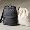 Mochila estructurada de poliester con tiras acolchadas, mochila de cuerdas y bolsa de lona sobre un piso de concreto claro